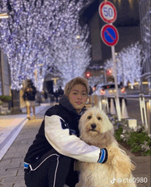 a man kneeling down with a dog in front of a sign that has the number 50 on it