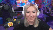 a woman wearing headphones is sitting in front of a microphone and smiling .