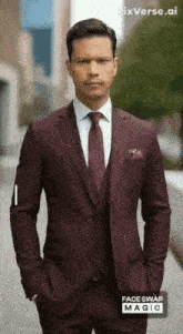 a man wearing a maroon suit and tie is standing with his hands in his pockets