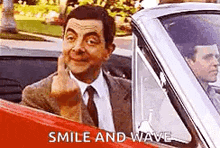 a man in a suit and tie is giving the middle finger while sitting in a car .