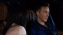 a man and a woman are sitting in the back of a car