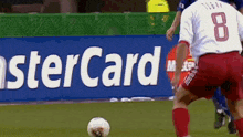 a soccer player with the number 8 on his back is kicking a ball