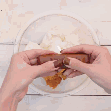 a person grates peanut butter into a glass bowl of whipped cream