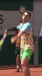 a tennis player swings a racket in front of a roland garros sign