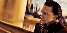 a man in a leather jacket is looking out of a window .