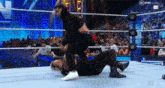 a man is laying on the ground in a wrestling ring while another man is standing on top of him .