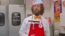 a man with a beard wearing an apron and a bow tie is holding a squeegee .