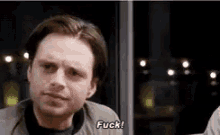 a man is sitting in front of a window talking to another man and says `` fuck '' .