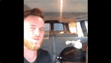 a man with a beard is sitting in the back seat of a van ..