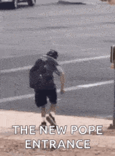 a man is walking across a street with the words `` the new pope entrance '' .