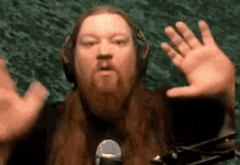 a man with long hair and a beard is wearing headphones and a microphone while making a funny face .