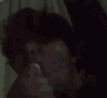 a close up of a person laying on a bed with a white curtain behind them .