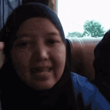 a woman wearing a hijab is smiling and looking at the camera .