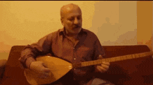 a man with a beard is playing a guitar while sitting on a couch .
