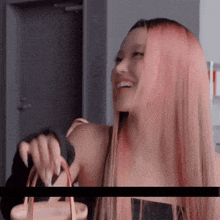 a woman with long pink hair is holding a purse