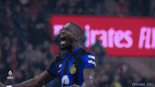 a soccer player screams in front of an emirates ad