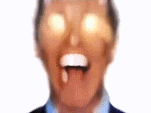 a close up of a man 's face with his tongue hanging out and his eyes glowing .