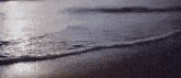 a close up of waves crashing on a sandy beach
