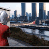 a woman in a red jacket stands in front of a city skyline and a body of water