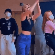 a group of people are dancing together in a room while wearing face masks .