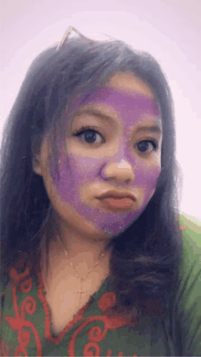 a woman with a purple mask on her face makes a funny face