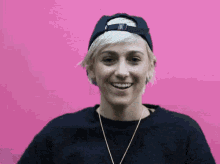 a woman wearing a baseball cap and a necklace is smiling .