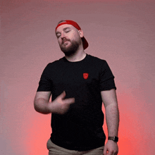 a man with a beard wearing a red hat and a black t-shirt with a red emblem on it