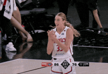 a female basketball player with the number 33 on her jersey applauds