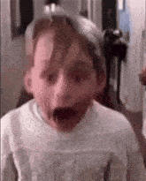 a young boy is making a funny face with his mouth open in a room .