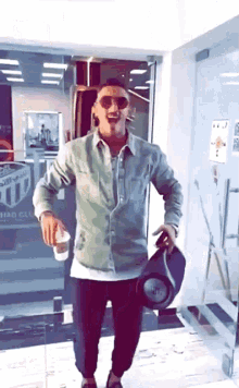 a man wearing sunglasses is holding a jbl speaker and a cup