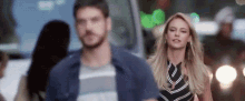 a man and a woman are walking down a street in the city .