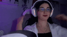 a woman wearing headphones and glasses is sitting in a chair and playing a video game .