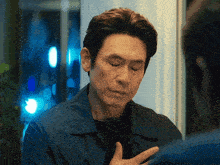 a man in a blue jacket is looking down with his eyes closed