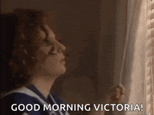 a woman is looking out of a window with the words `` good morning victoria '' written on it .