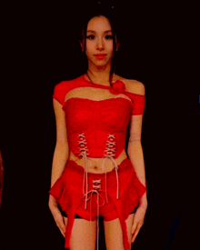 a woman in a red crop top and shorts with lace up front