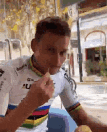 a man in a cycling jersey is eating a sandwich with a toothpick in his mouth .