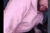a man wearing a pink shirt and tie is laying down .