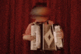 a person playing an accordion with a red curtain behind them