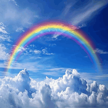 a rainbow is visible in the blue sky above clouds