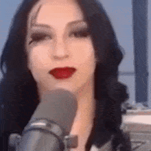 a woman is talking into a microphone with red lipstick .