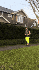 a man in yellow pants is riding a scooter on a sidewalk in front of a house
