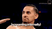 a shirtless man is screaming internally while standing in a dark room .