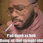 a man with glasses is smoking a cigarette and the caption says y'all dumb as hell doing all that straight shit