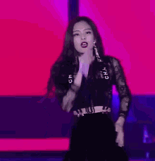 a woman is singing into a microphone and flexing her muscles