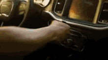 a person is driving a dodge charger with their hand on the steering wheel .
