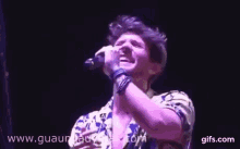 a young man is singing into a microphone on a stage .