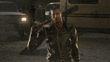 a man in a leather jacket is holding a baseball bat and smiling
