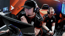 a man wearing headphones and a syner shirt looks at a monitor