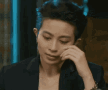 a man with blue hair has his hand on his face