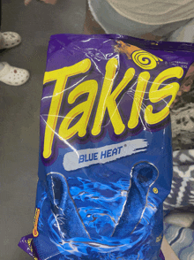 a person holding a bag of takis blue heat chips